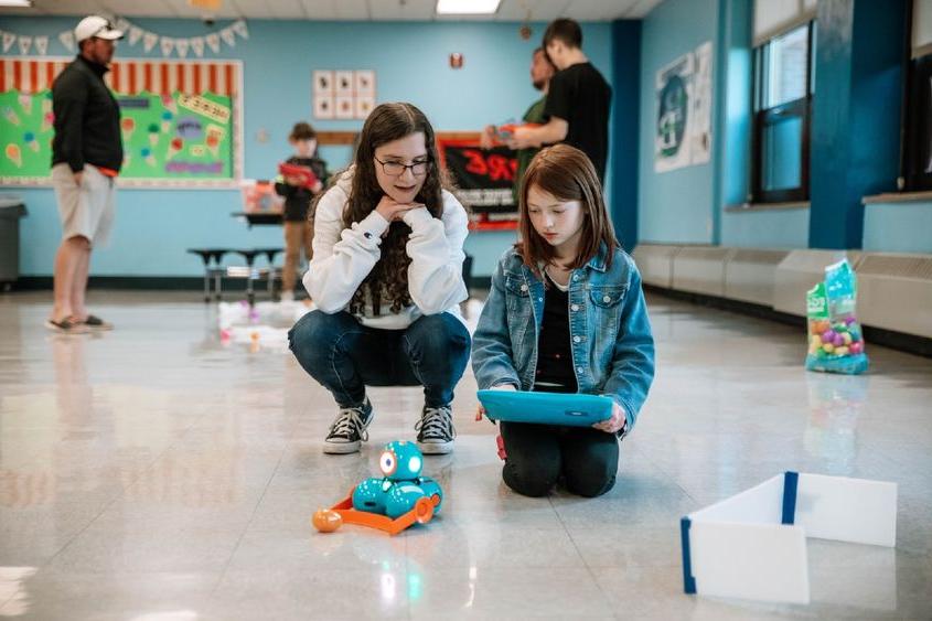 College student helps elementary school student with robot